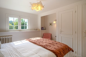 Ein Schlafzimmer mit Bett, Fenster, Tür und einer Lampe.