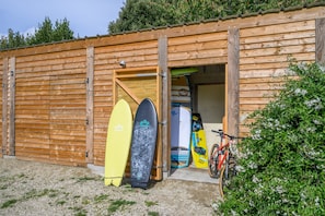 Ein Holzgebäude mit einer Tür, drei Surfbrettern und einem Fahrrad.