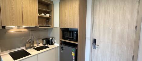 Una cocina moderna con armarios de madera, microondas integrado, refrigerador y un lavamanos con grifo.