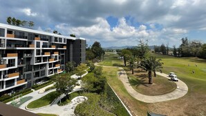 Ein modernes, mehrstöckiges Gebäude mit Balkonen, einem Golfplatz und wolkenlosem Himmel.