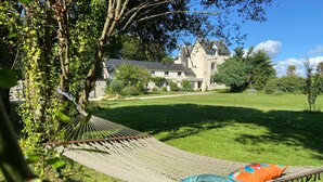 A hammock on a grassy lawn with a building in the background.