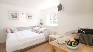 A bedroom with a bed, bedside table, and a small table with a cup and snacks. - Studio 'Villa Prat Bras - Sea View' with Shared Garden and Wi-Fi (Clohars-Carnoët)