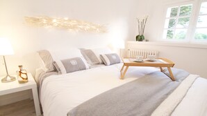 A bedroom with a bed, bedside table, lamp, and window with view.