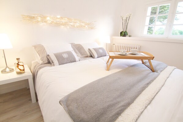 A bedroom with a bed, bedside table, lamp, and window with view.