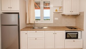 Una cocina con armarios blancos, un refrigerador de acero inoxidable, una ventana con vistas, un fregadero y un horno.