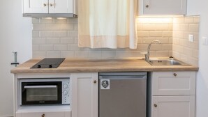 A compact kitchen with white cabinets, a built-in oven, a dishwasher, and a wooden countertop. - Holiday Home 'Anemologio 204 Tinos' with Sea View, Wi-Fi and Air Conditioning (Laouti)