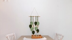 A dining table with four chairs, a hanging plant, and a basket on the table. - Holiday Home 'Anemologio 204 Tinos' with Sea View, Wi-Fi and Air Conditioning (Laouti)