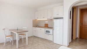 A kitchen with white cabinets, a wooden countertop, a built-in oven, and a dining table with chairs.