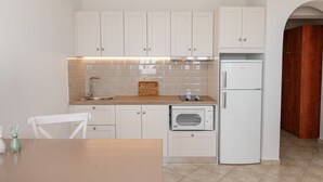 A kitchen with white cabinets, a built-in oven, a refrigerator, and a wooden countertop.