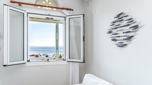 A room with a white couch, a window with a view of the sea, and a wall decoration of fish. - Holiday Home 'Anemologio 102 Tinos' with Sea View, Wi-Fi and Air Conditioning (Laouti)