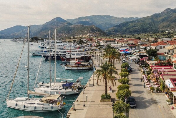 Un puerto deportivo con barcos amarrados, un paseo marítimo y edificios con tiendas.