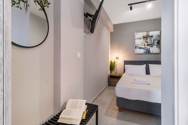 Une chambre à coucher avec un lit, une table de chevet et un téléviseur fixé au mur.