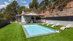 Una casa con piscina, mobiliario exterior y vistas a árboles y colinas.