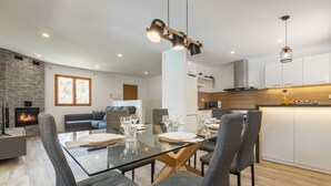 Una sala de estar moderna con una mesa de comedor de vidrio, sofás grises y una chimenea.