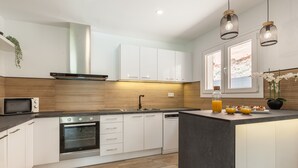 Una cocina moderna con armarios blancos, horno empotrado, microondas y pileta.