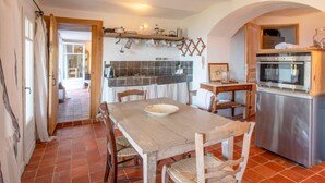 A kitchen with a wooden table, chairs, a refrigerator, and a tiled backsplash. - Apartment "La maison de Constance" with Sea View, Terraces and Wi-Fi (Cavalaire-sur-Mer)