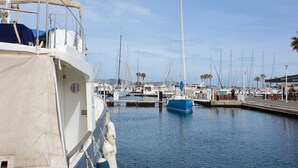 A marina with boats docked, a building with a covered area, and palm trees in the background. - Apartment "La maison de Constance" with Sea View, Terraces and Wi-Fi (Cavalaire-sur-Mer)