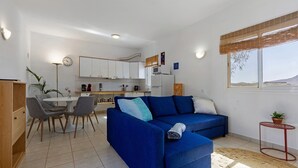 A compact living space with a sofa, dining table, and kitchenette.