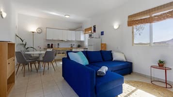 A compact living space with a sofa, dining table, and kitchenette.