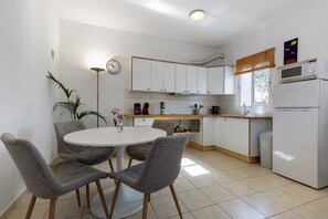 A kitchen with white cabinets, a round table, and four grey chairs. - Vacation Home "La Finca Las Estrellas" with Mountain View, Garden & Wi-Fi (Tarajalejo)