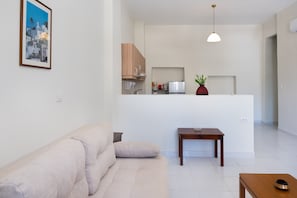 Un soggiorno moderno con un divano, un tavolino e una zona cucina sullo sfondo.