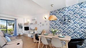 Un salon moderne avec un canapé, une table à manger, des chaises et un mur décoré d’un motif.