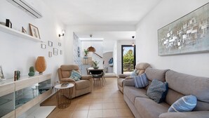 Un salon moderne comprenant un canapé, des fauteuils, une table à manger et un coin cuisine.