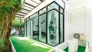 A modern building with large glass windows, a green artificial lawn, and a white exterior. - Pool villa at Kamala Regent by Lofty (Kamala)