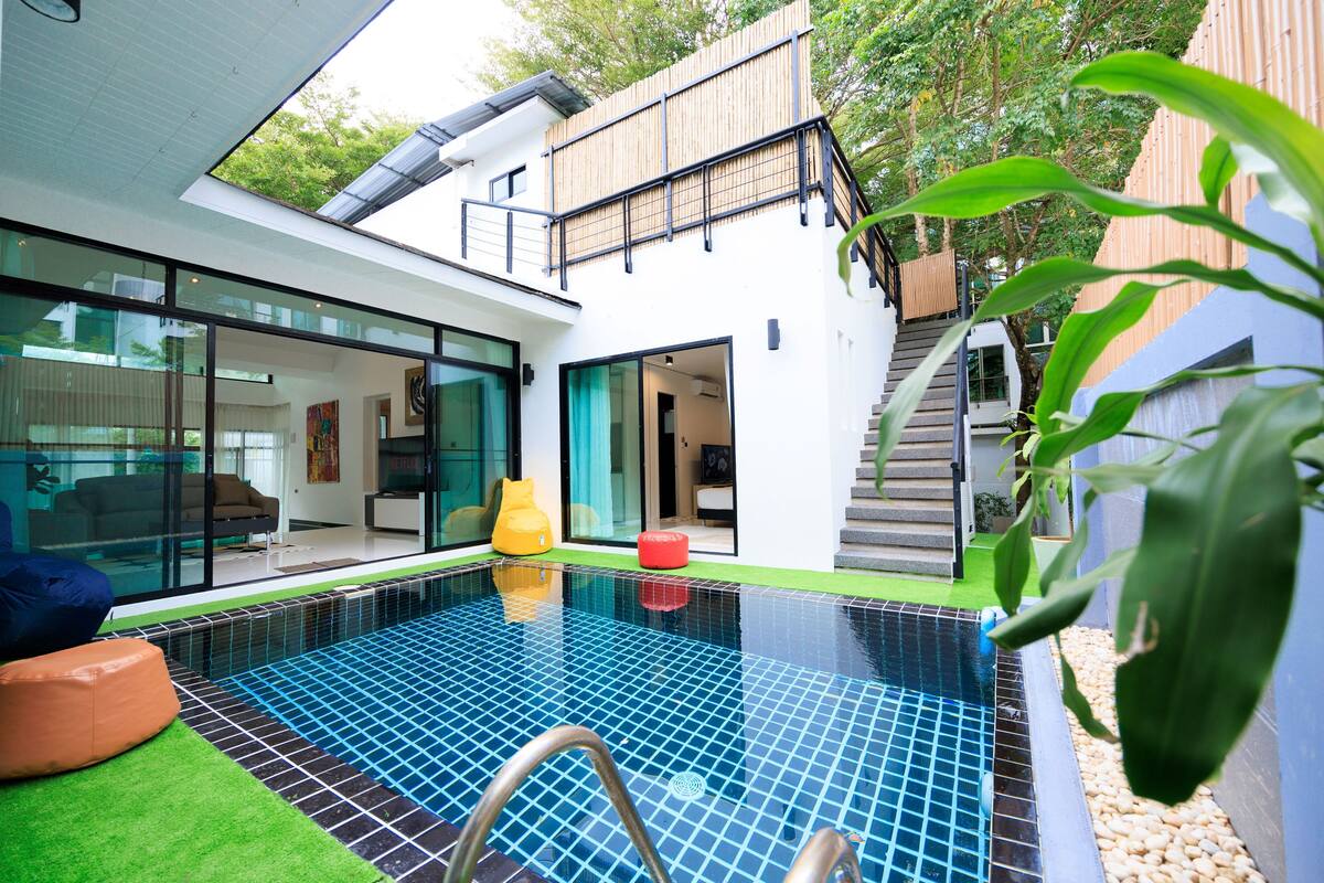 A modern house with a swimming pool, large glass windows, and a wooden deck.