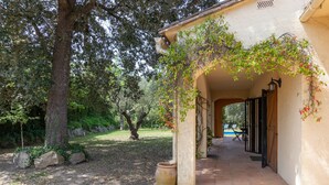 A covered outdoor area with a stone floor, a large tree, and a building with a tiled roof. - Villa 'Del Sol' with Mountain View, Wi-Fi and Air Conditioning (Santa cristina D'aro)