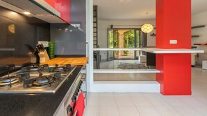 A modern kitchen with a gas stove, red accents, and a view of the outdoors. - Villa 'Del Sol' with Mountain View, Wi-Fi and Air Conditioning (Santa cristina D'aro)