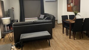 A living room with a sofa, a dining table with chairs, a lamp, and a ceiling fan. - Quiet and comfortable 2 bedroom apartment, 65 inch Smart TV (Wodonga)