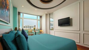 Een moderne hotelkamer met een groot bed, een aan de muur bevestigde televisie en uitzicht op de stad.