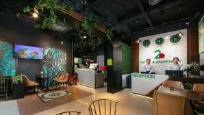 Een hotel receptie met een modern design, inclusief een receptiebalie, een zithoek en een wand met klokken die verschillende steden weergeven.