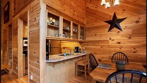 A wooden interior with a kitchen area, bar, and dining table. - Mountain Memories - Cabin near Blue Ridge Parkway (Boone)