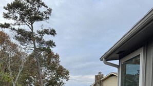 A wooden deck with a round table and four chairs, overlooking a scenic view of trees and a distant landscape. - •Treehouse by The Lake• (Chattanooga)