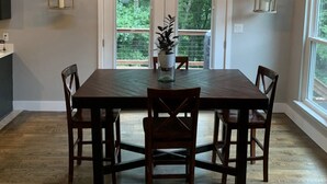 A dining area with a wooden table and chairs, a hanging light fixture, and a sign above the door that reads "GARDEN". - •Treehouse by The Lake• (Chattanooga)