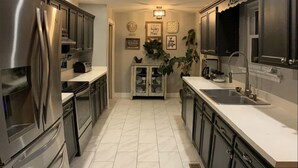 A modern kitchen with stainless steel appliances, dark cabinetry, and a white tiled floor. - •Treehouse by The Lake• (Chattanooga)