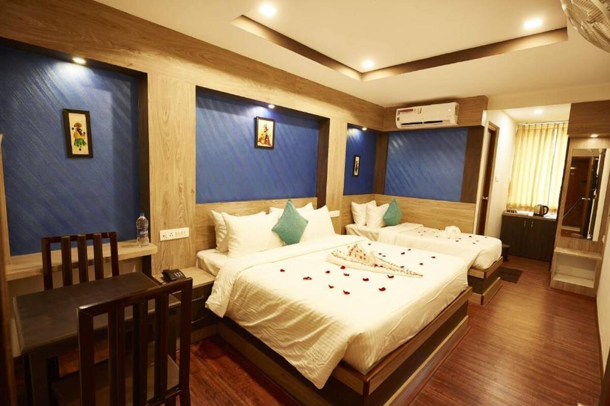 A hotel room with two beds, a wooden headboard, a small table, and a desk.