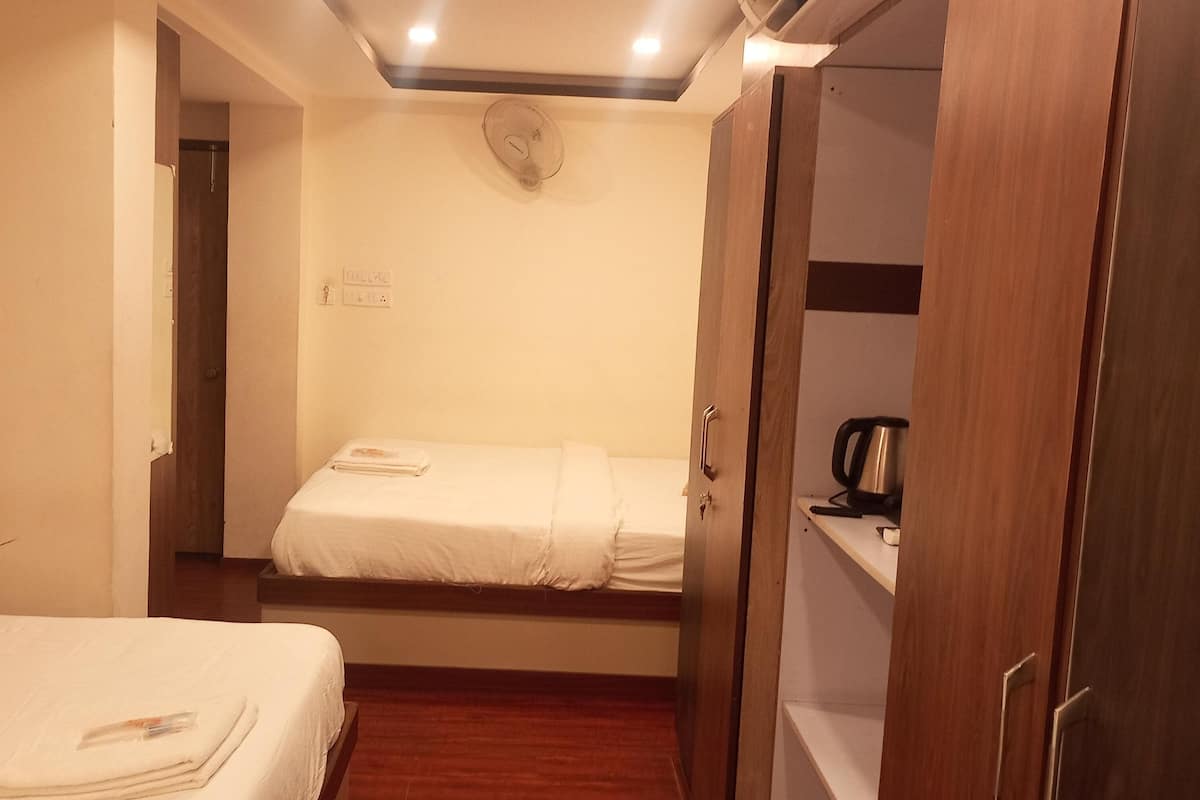 A small, compact hotel room with a bed, a bedside table, and a wardrobe.