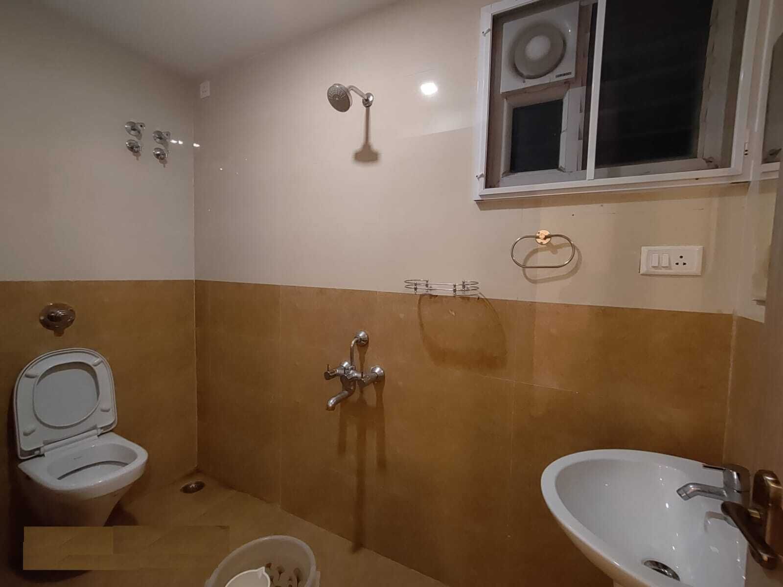 A bathroom with a toilet, a shower, and a sink.