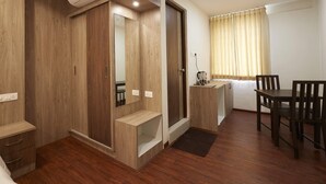 Una habitación compacta con un armario de madera, un escritorio pequeño, una silla y una mesa de comedor.