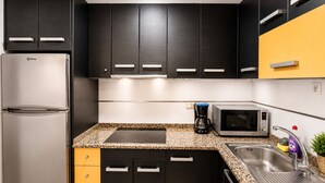 A modern kitchen with a stainless steel refrigerator, black cabinets, a microwave, a coffee maker, and a granite countertop. - Apt  near center & port (Torrevieja)
