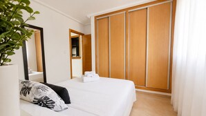 A bedroom with a bed, a bedside plant, a mirror, and a wardrobe. - Apt  near center & port (Torrevieja)