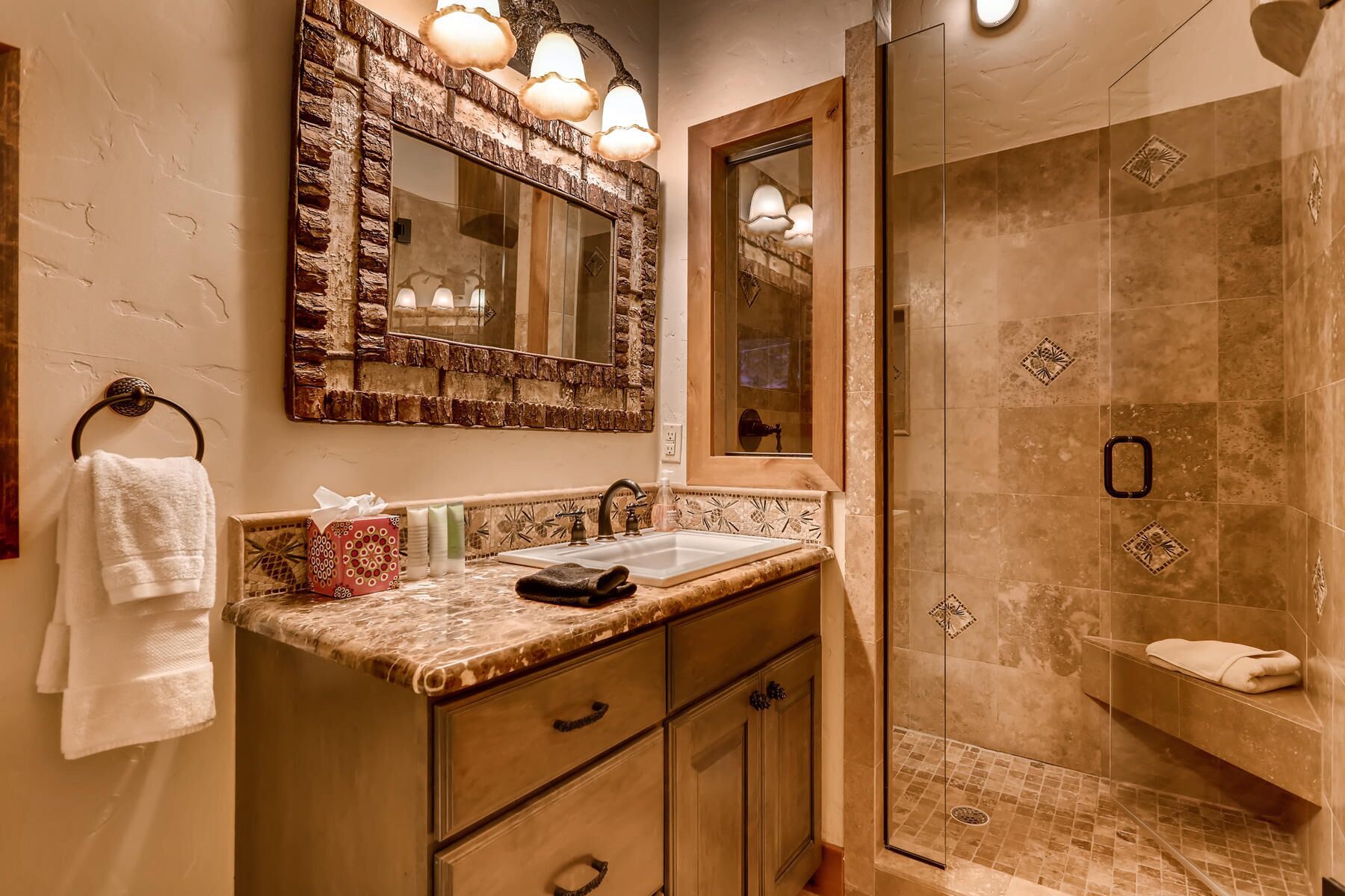 Une salle de bain avec un mur en pierre, un lavabo avec un miroir et un espace douche.