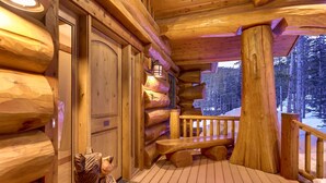 A log cabin with a wooden deck, a bench, and a view of the snowy forest. - STUNNING custom log home, 4 en-suites, amazing views, hot tub, pool table! (Breckenridge)