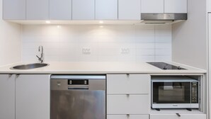 Une cuisine moderne avec des meubles blancs, un lave-vaisselle en acier inoxydable et un four à micro-ondes encastré.