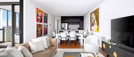 A modern living room with a sofa, coffee table, TV, and artwork.