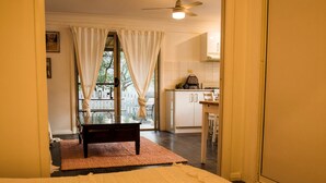 Un dormitorio con una cama grande, una mesita y vistas a un balcón y una zona de cocina.