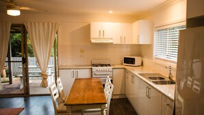 Una cocina con armarios blancos, una mesa de comedor de madera y un microondas empotrado.